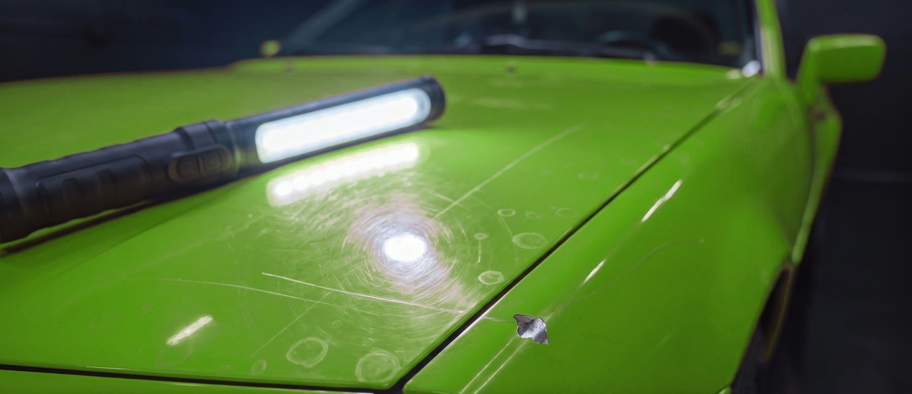 Close-up of paint under an inspection light showing swirl marks and scratches